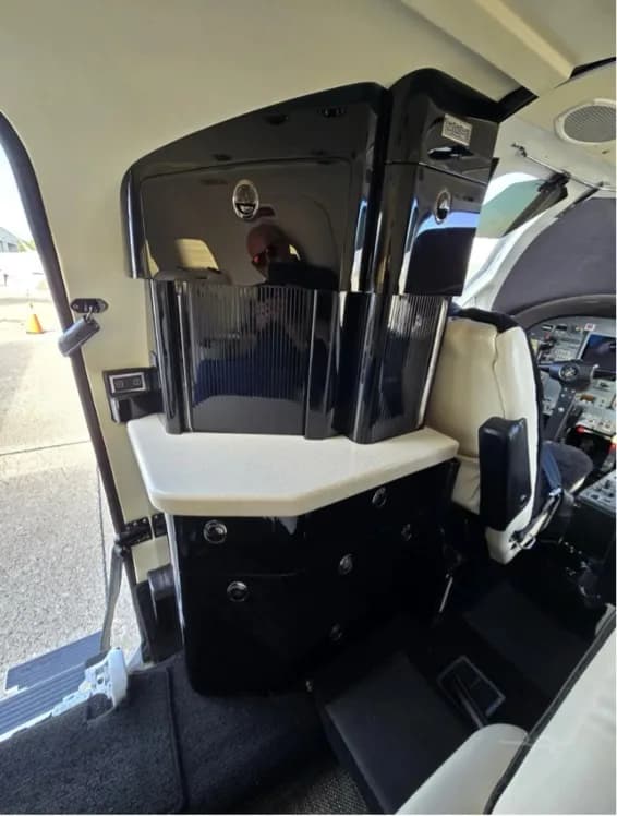 A view of the jet's interior galley and storage area, with a partial view of the cockpit instruments.
