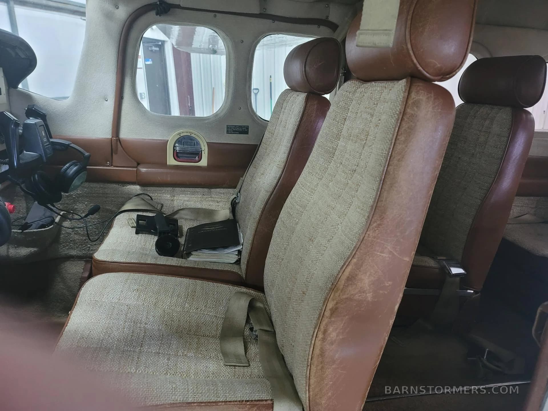 The aircraft's interior cabin with brown and beige fabric seats and side panels.