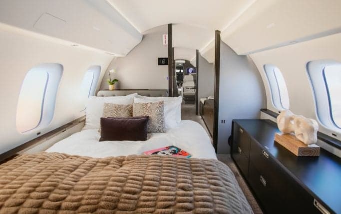 Interior of the Global 7500 cabin with a sofa, TV, and a view towards the bedroom area.