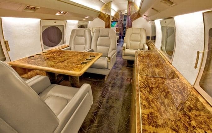 Aircraft cabin with leather seats and wood trim.