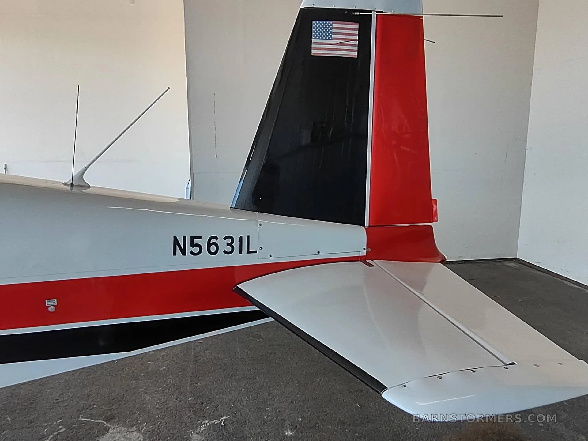 A close-up of the tail section of a white, red, and black aircraft with tail number N5631L and an American flag decal.