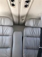The interior of the aircraft features gray leather seats and overhead vents.
