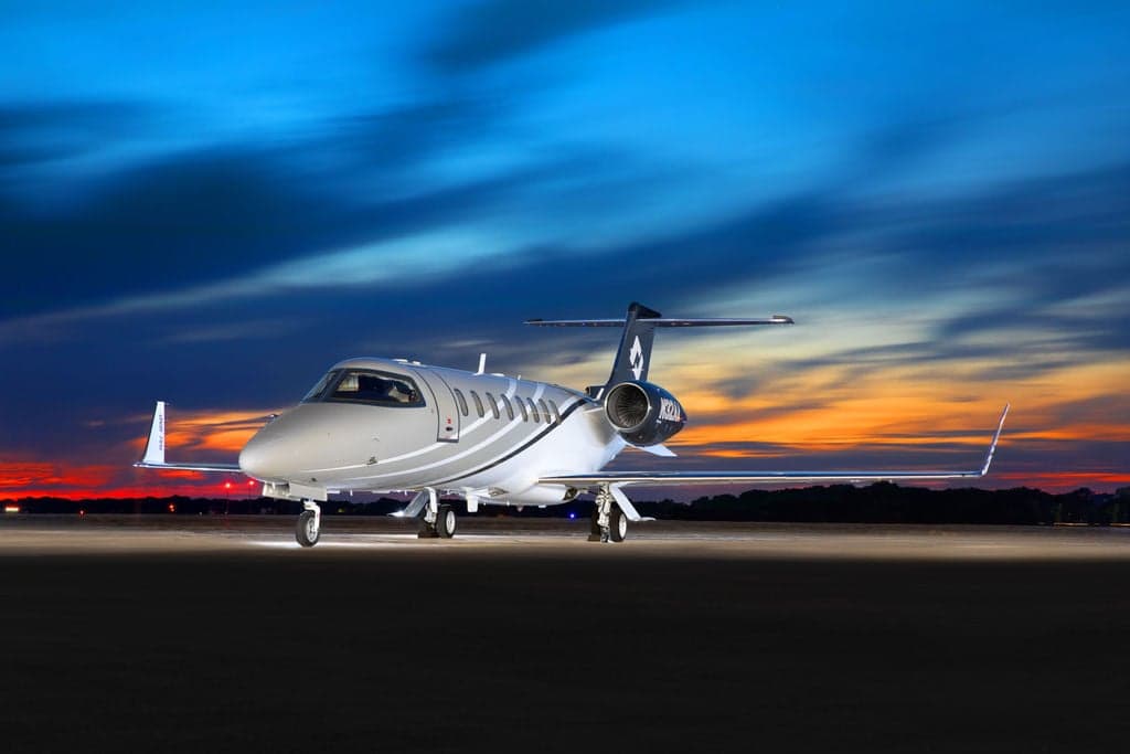A Learjet 45XR aircraft parked on the tarmac at sunset.