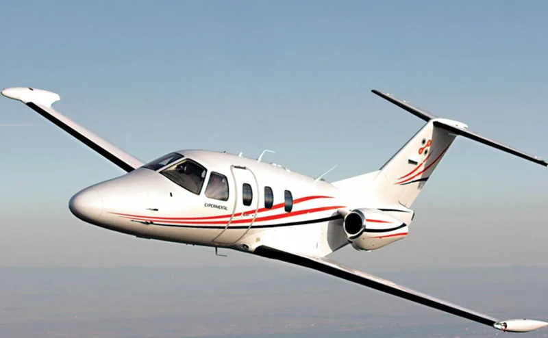 A white Eclipse jet with red stripes in flight.