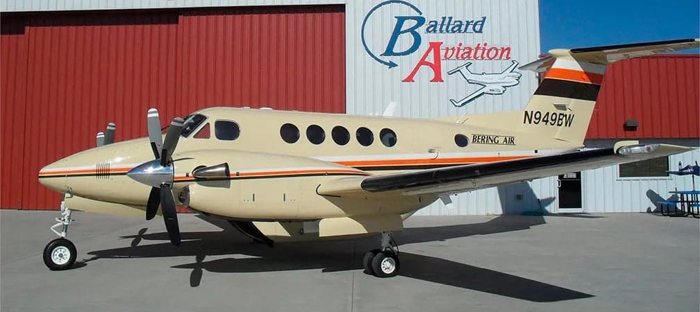 King Air turboprop aircraft with Bering Air livery parked in front of a hangar.