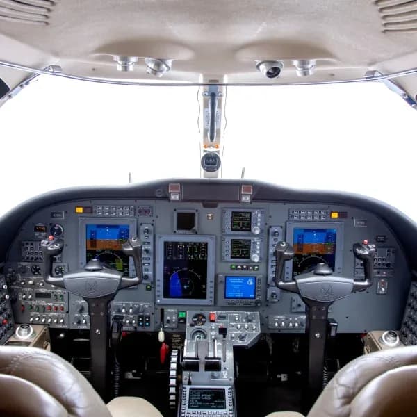 The aircraft cockpit features a modern glass panel display with multiple screens and control yokes.