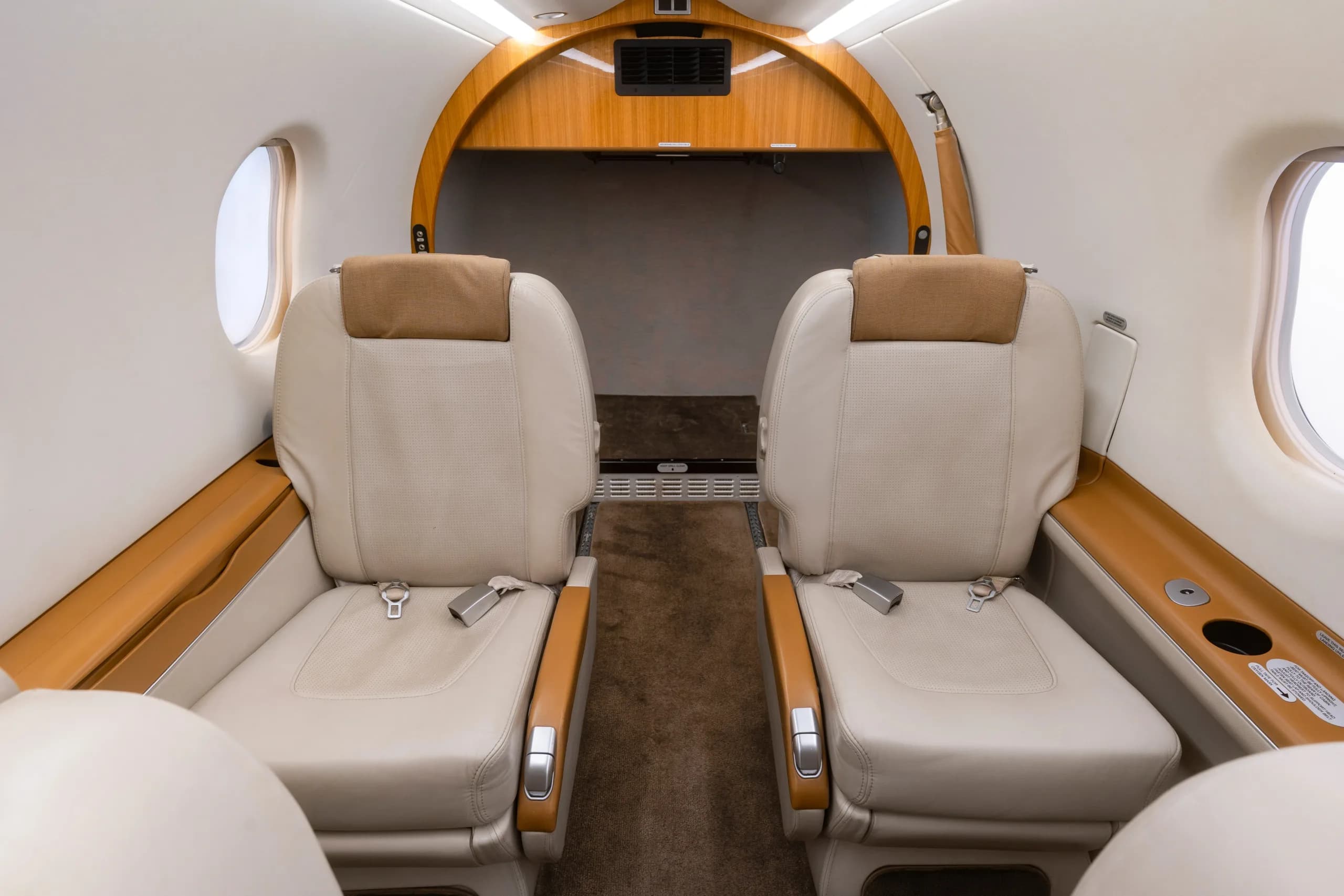 A view of two beige leather passenger seats in the Pilatus PC-12 cabin, facing forward.