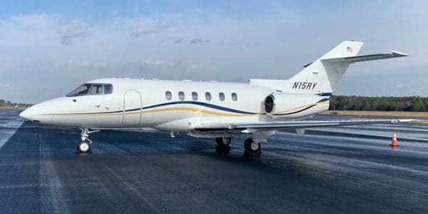 A white and blue Falcon jet is parked on the tarmac.
