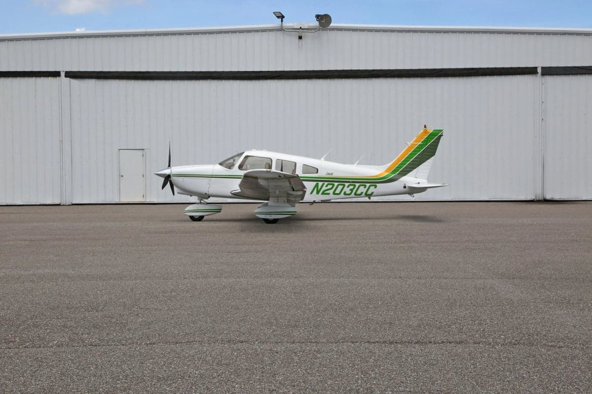 Side view of a white and green Piper Dakota aircraft on the tarmac.