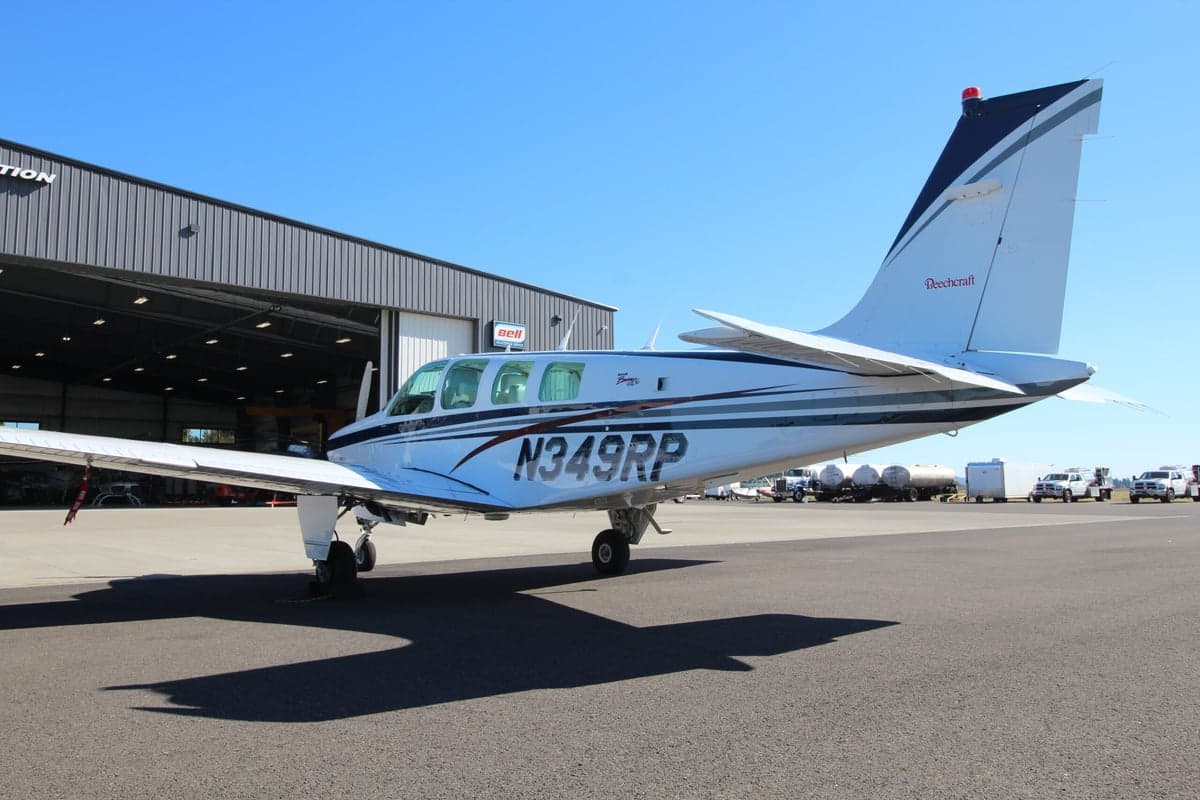 Side view of a Beechcraft Bonanza aircraft with registration N349RP on the tarmac in front of a hangar.