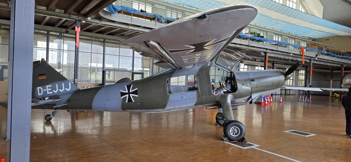 Side view of a gray and green aircraft with German markings in a hangar.