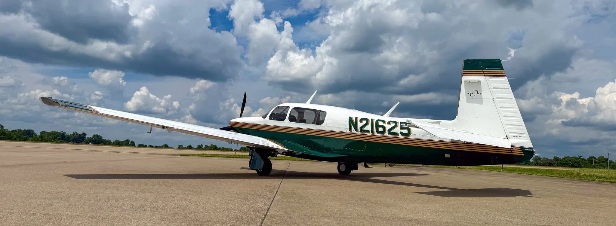 A side view of the white and green Mooney M20 aircraft with registration N21625 on an airfield.