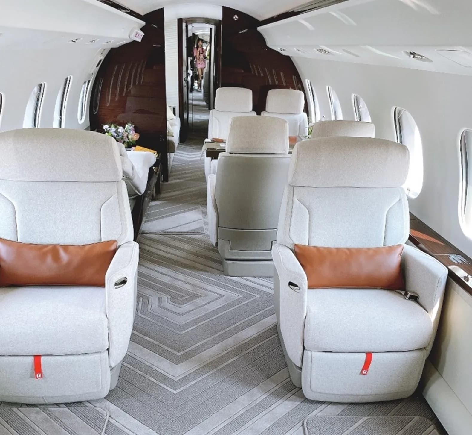 View of the aircraft interior with white leather seats and brown pillows.