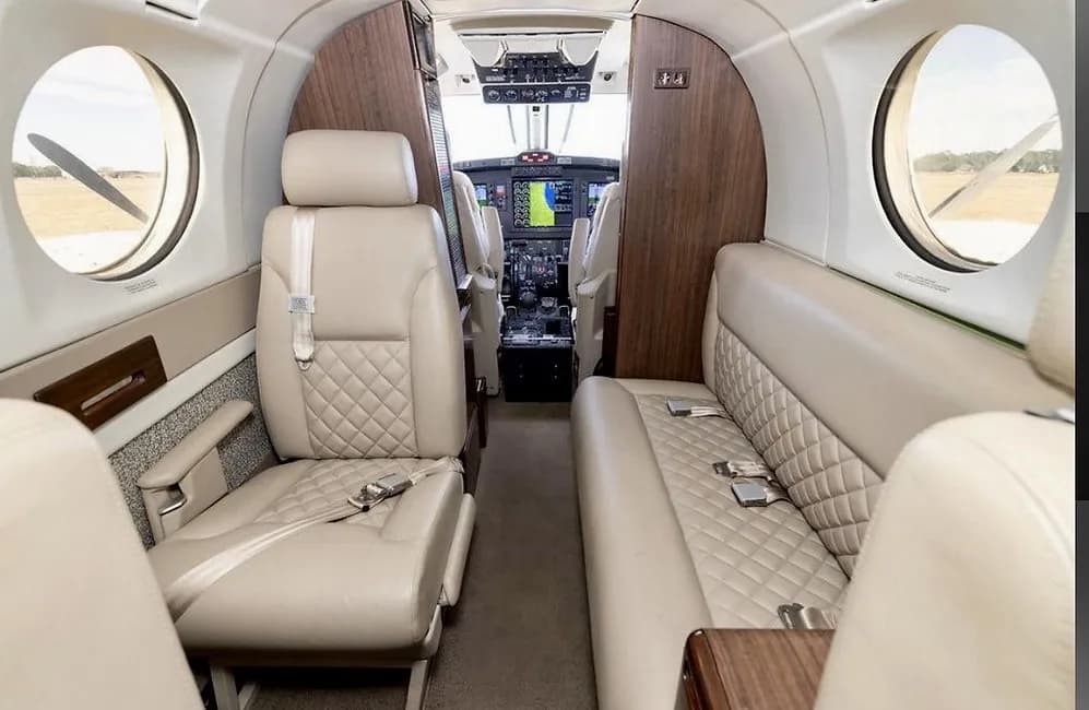 Interior of a Beechcraft King Air 360ER with tan leather seats and a view of the cockpit.