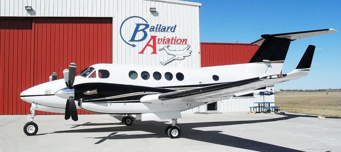 A King Air aircraft parked in front of a Ballard Aviation hangar.