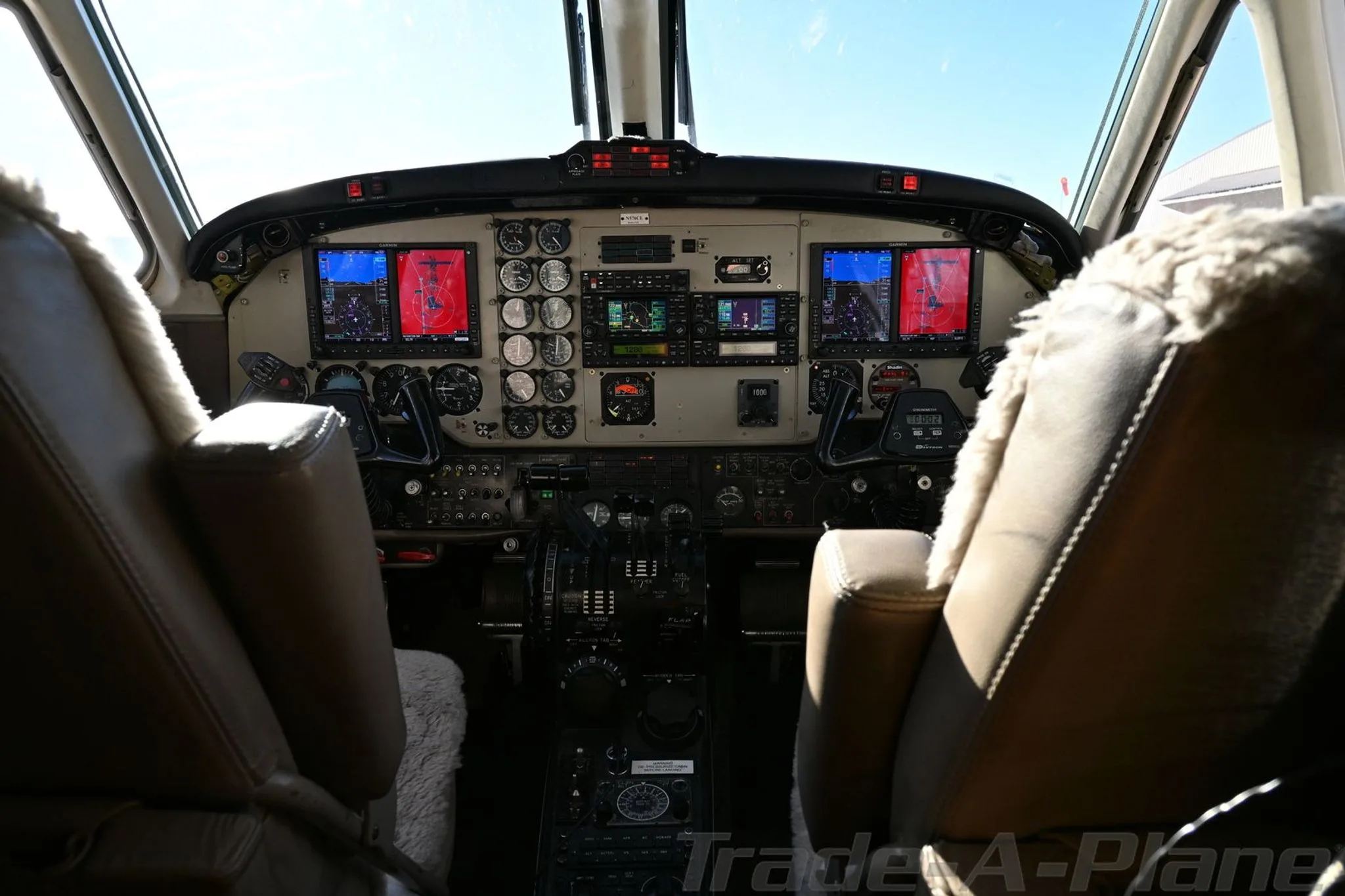 The cockpit of a Beechcraft King Air 200, showing the instrument panel with two large red displays and pilot seats.