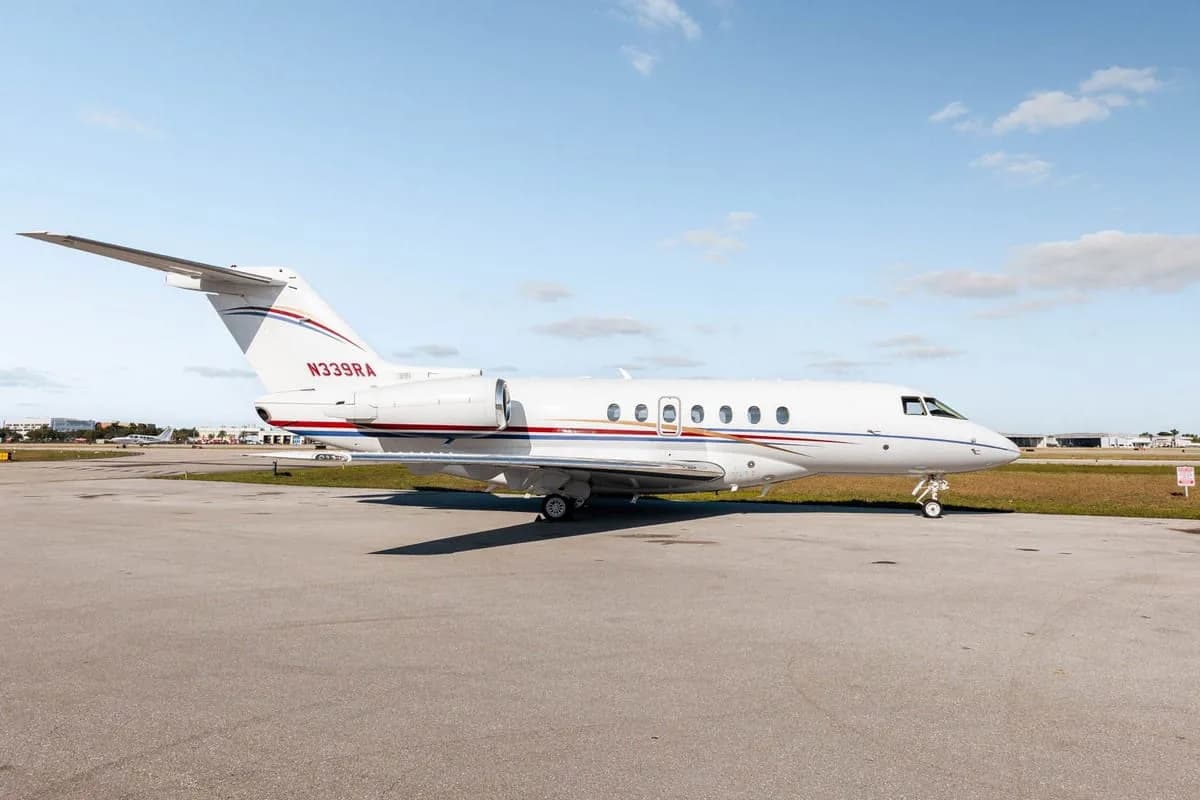 A white Hawker 800XP business jet with red and blue stripes, registration N339RA, parked on the tarmac.
