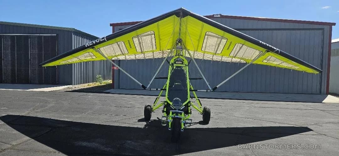 A front view of a yellow and black Revolt ultralight trike on an airfield tarmac.