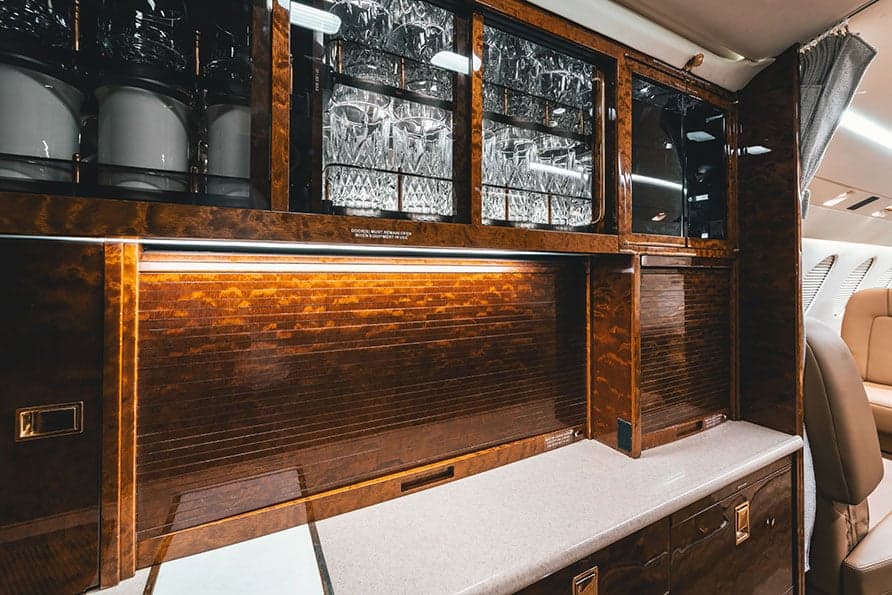 A cabinet in the Falcon 7X cabin features glassware and storage compartments.