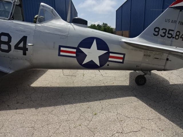 Close-up of the side of the silver T-6 Texan aircraft showing the US Air Force star and tail number.