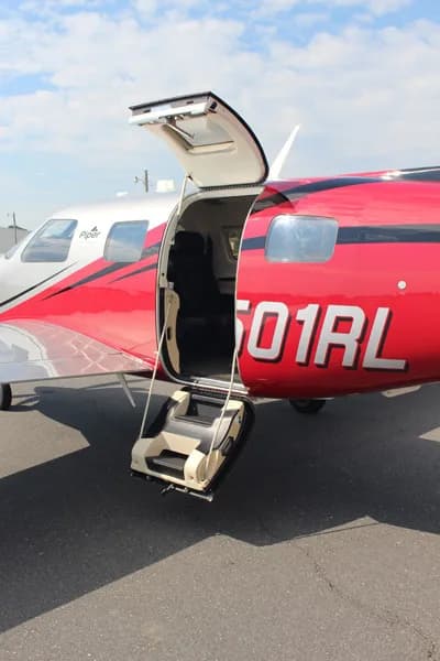 A side view of the Piper M600 aircraft, N501RL, with its cabin door open and integrated stairs extended.