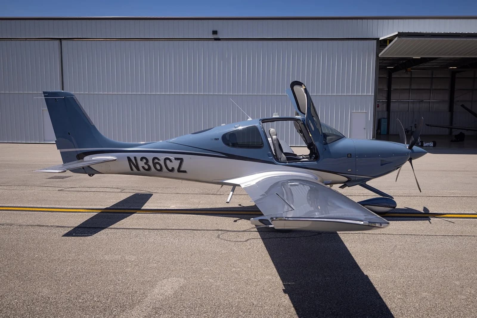 A Cirrus SR22T aircraft with open doors is parked on the tarmac.