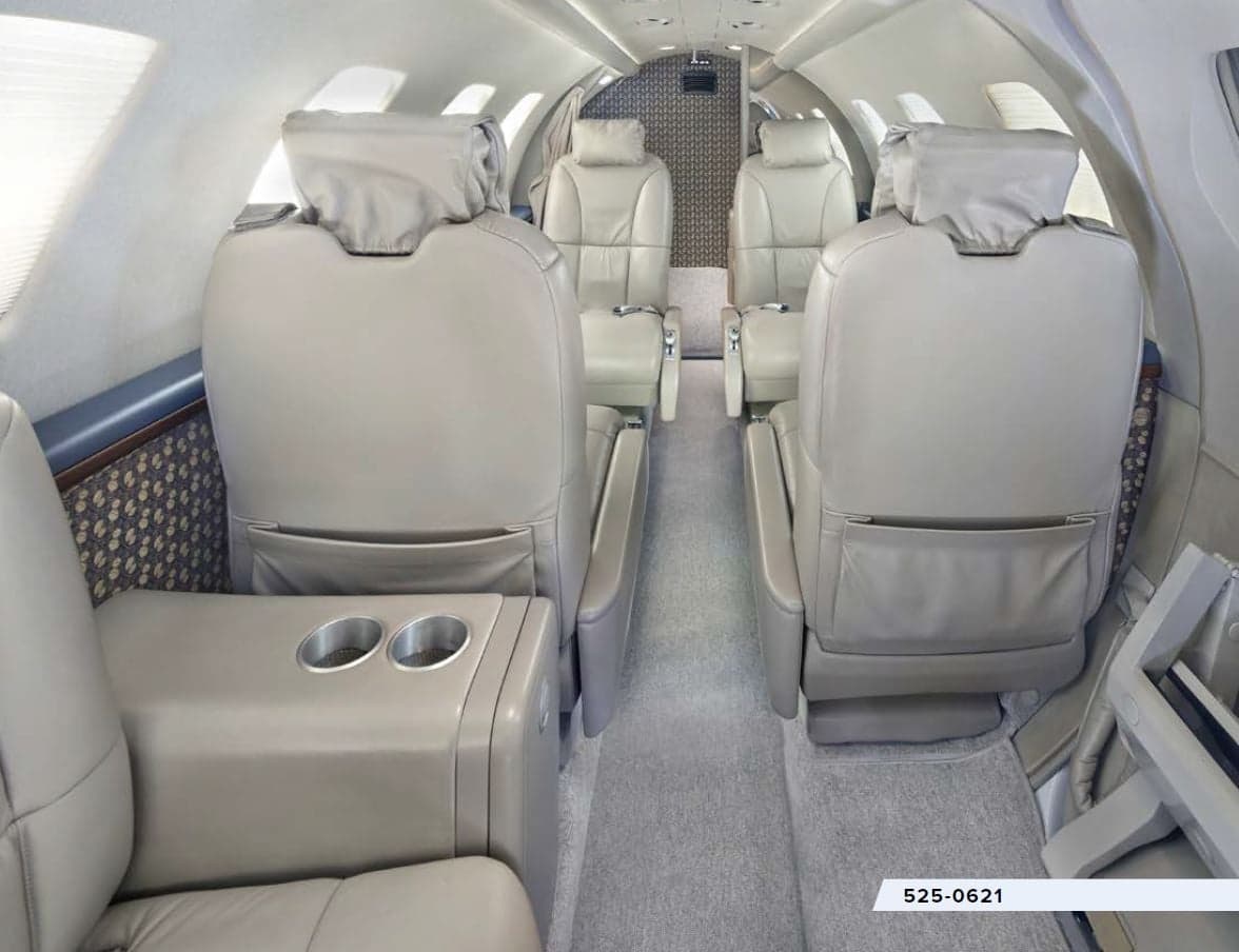 The interior of the aircraft features leather seats and a side table with cupholders.