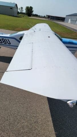 A Cessna Centurion aircraft with a blue and white paint scheme is parked inside a hangar.