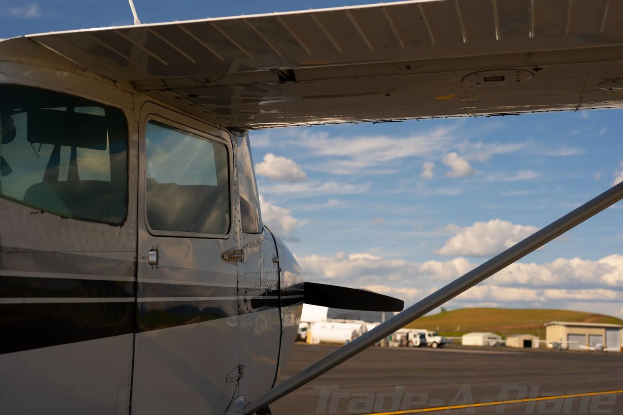 A close-up view of the fuselage and wing of a white Cessna 172, showing the side windows and strut.