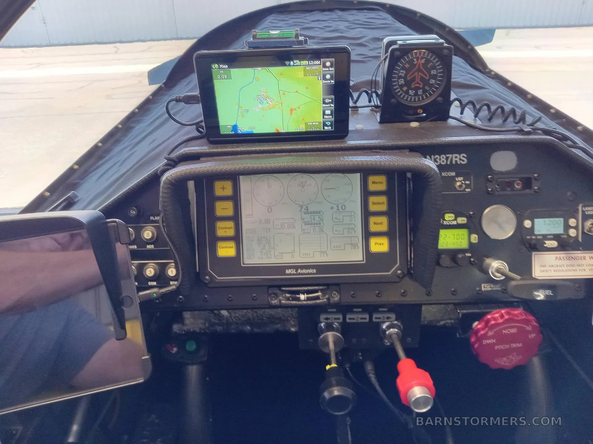 A close-up view of the aircraft's cockpit, displaying an MGL Avionics screen with flight data and a GPS map on a tablet.