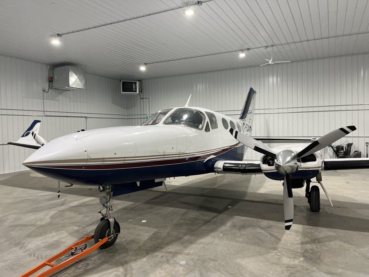A white and blue twin-engine aircraft is parked in a hangar.