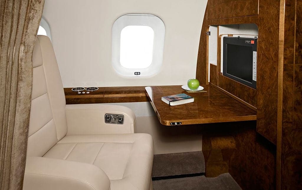 A comfortable aircraft seat with a fold-out table and entertainment system.