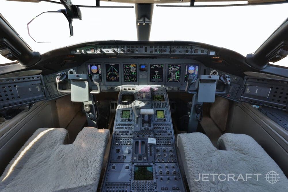 The cockpit of a business jet, showing the instrument panel, yokes, and control console.