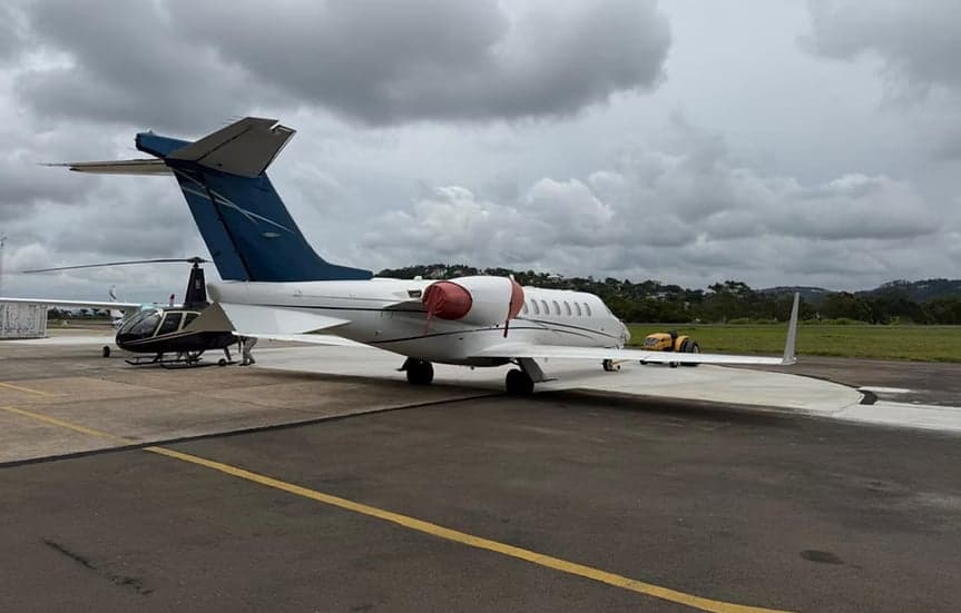Rear side view of a white Learjet with blue tail on the tarmac.
