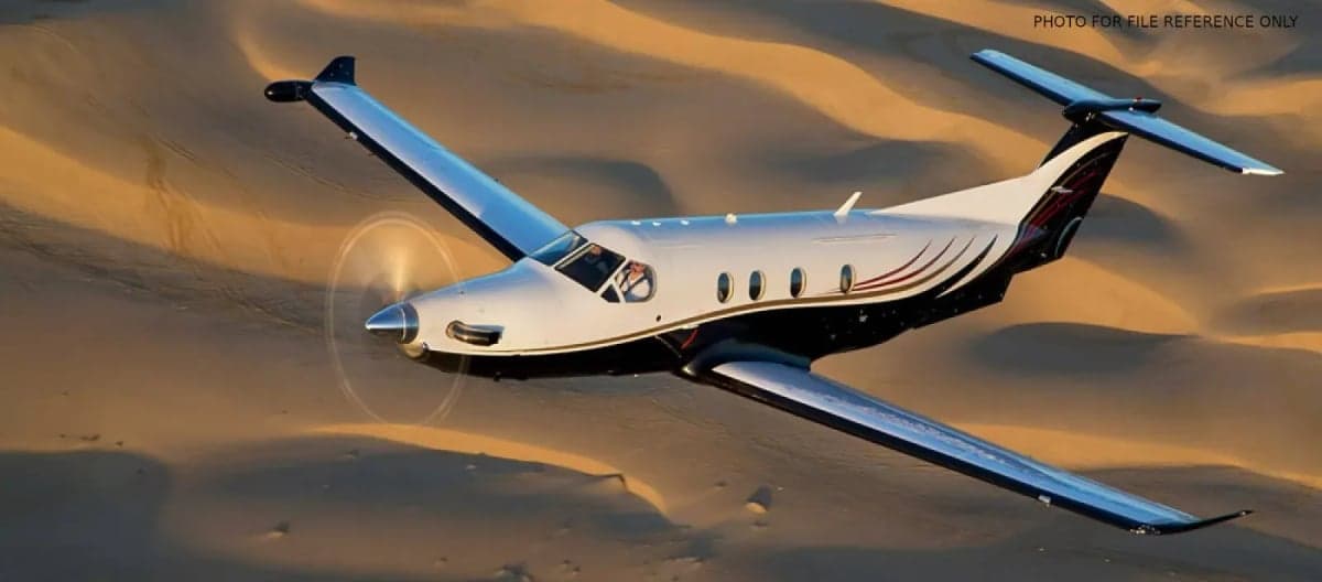 A Pilatus PC-12 in flight over a desert landscape.