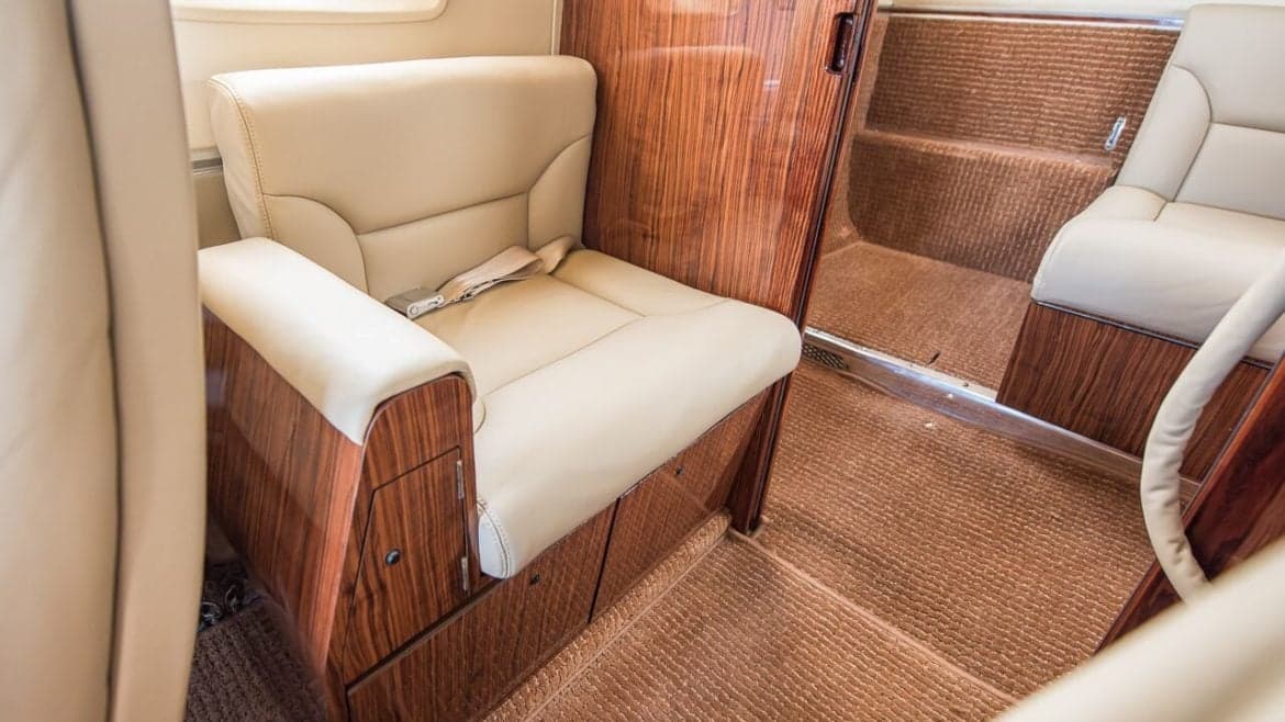 Aircraft interior with a leather seat and wood trim.