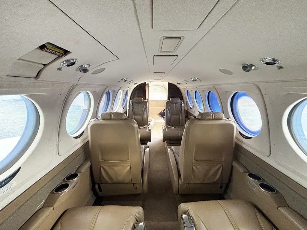 The aircraft's interior cabin with tan leather seats, looking towards the rear of the plane.