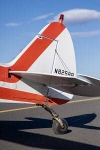 Tail section of a Piper Super Cub aircraft with a red and white paint scheme, showing the tail number.