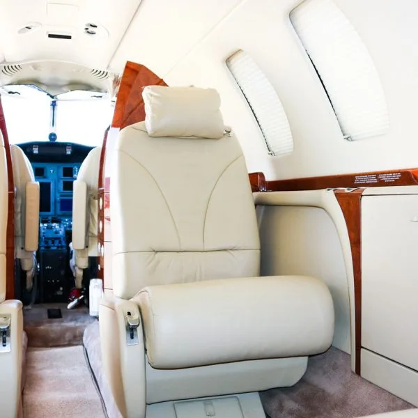 A single light beige leather cabin seat with a view towards the cockpit.