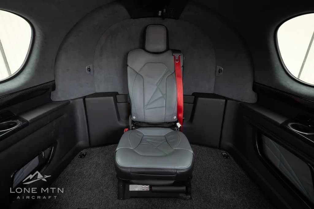 A view of the single rear seat in the Cirrus Vision Jet cabin with a red seatbelt.