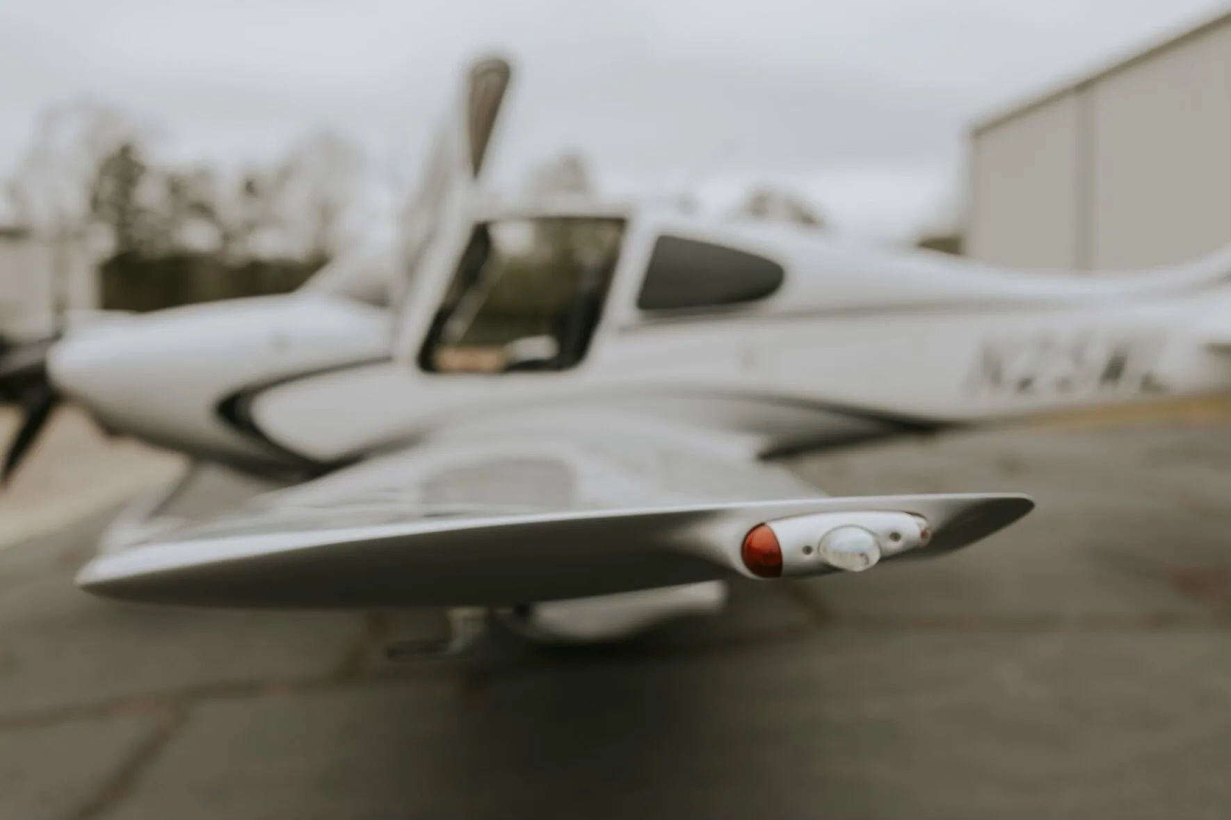 A close-up, blurred view of the wingtip of a silver Cirrus SR22 GTS, showing the navigation light.