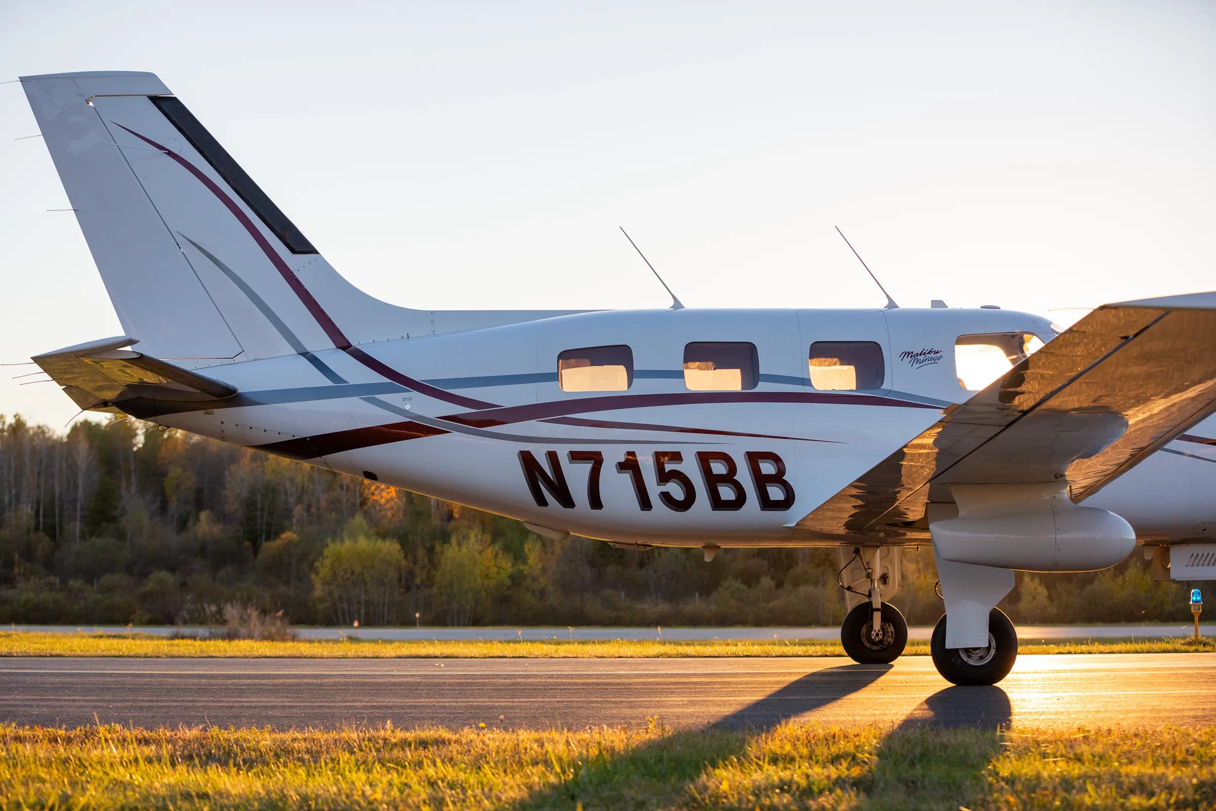 A close-up side view of the tail and fuselage of Piper Malibu Mirage N715BB at sunset.