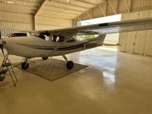 Cessna 172 Skyhawk with tail number N5555D parked inside a hangar on a rug.