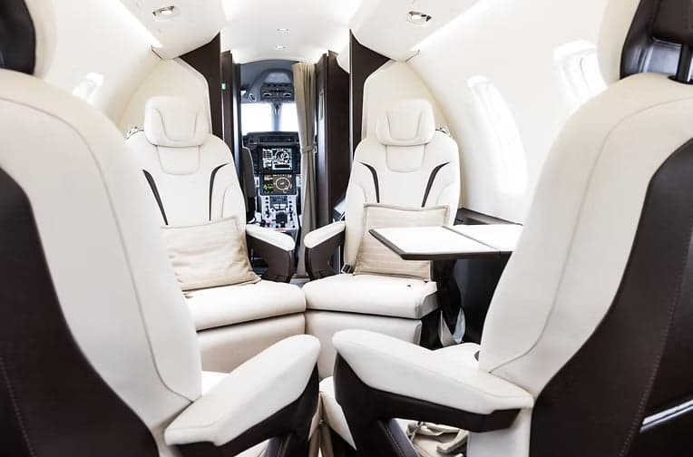 A view of the interior of a Pilatus PC-24 with white leather seats.