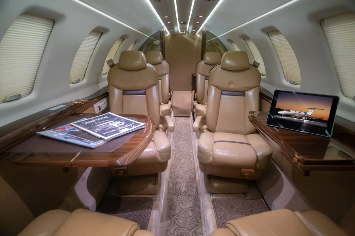 A single tan leather passenger seat next to a window in an aircraft cabin.