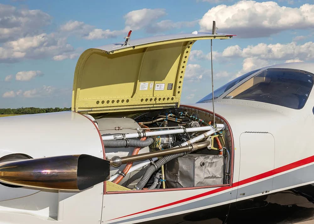 A close-up view of the open engine cowling of the TBM 900 series aircraft, revealing the engine and internal components.