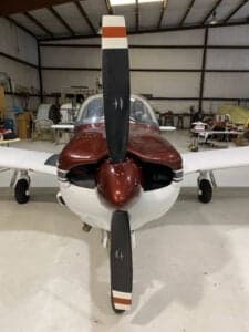 Front view of N2247M's nose and propeller in a hangar setting.