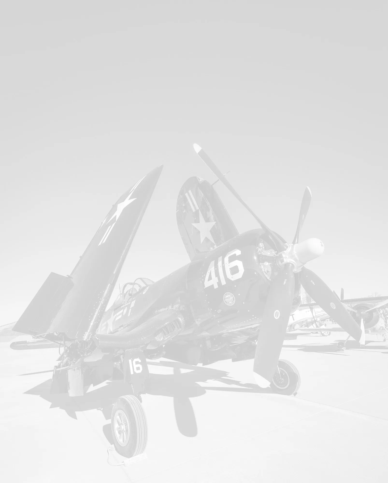 A faded, low-contrast image of a vintage propeller aircraft, possibly a Corsair, with "416" on its nose.