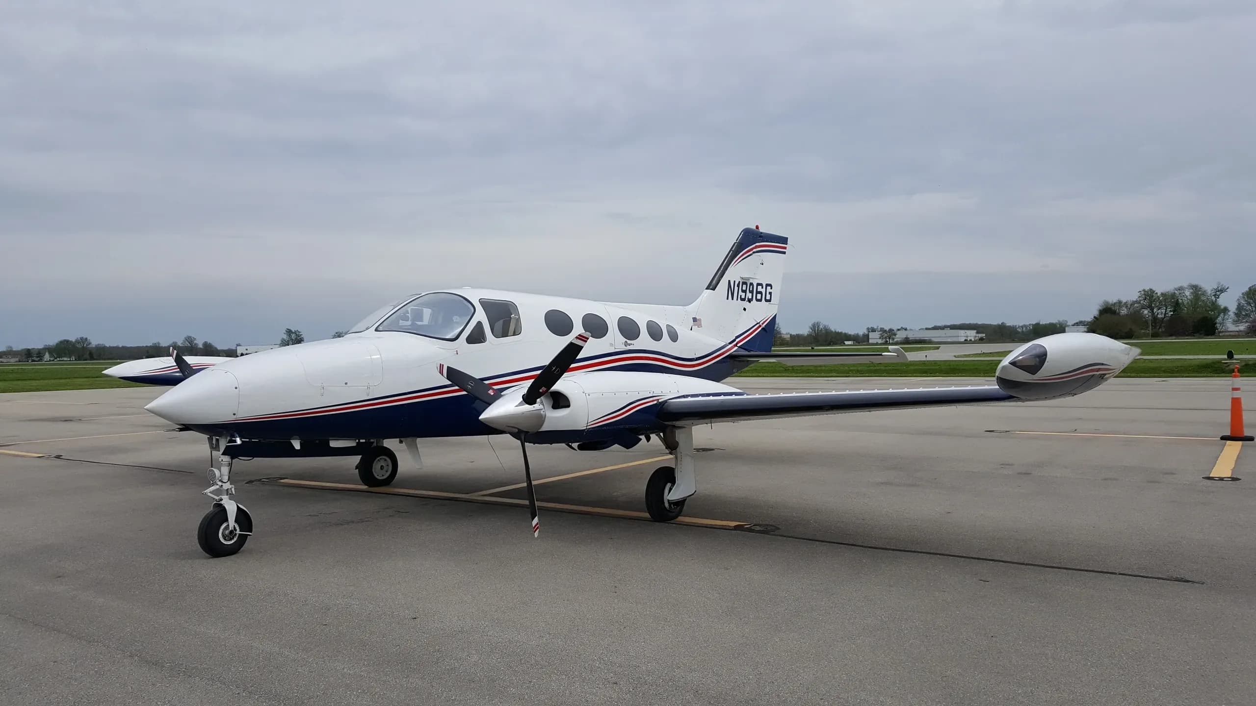 A side view of a white and blue twin-engine Cessna 414 Chancellor aircraft (N1996G) parked on an airfield.