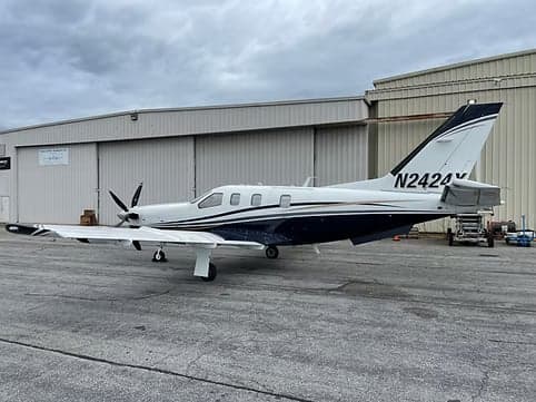 Side view of a turboprop aircraft with registration N2424X parked in front of a hangar.